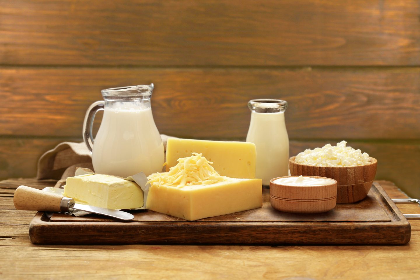 Milk, butter and cheese displayed on a wooden chopping board