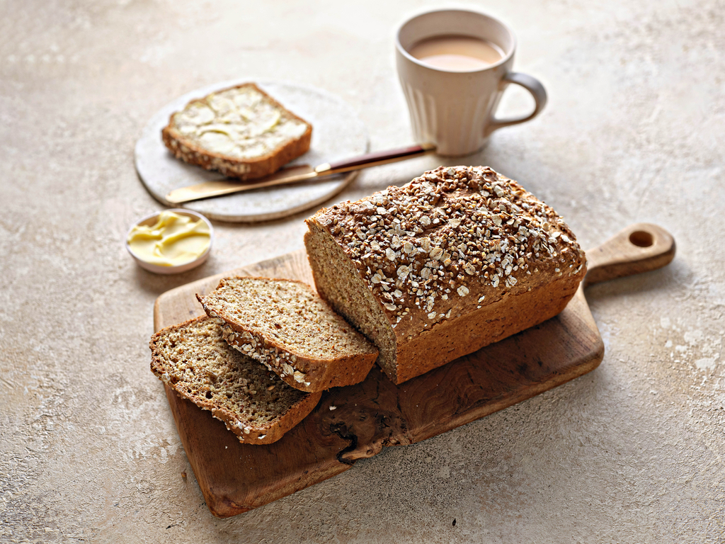 A wooden board with a loaf of wholemeal brown bread