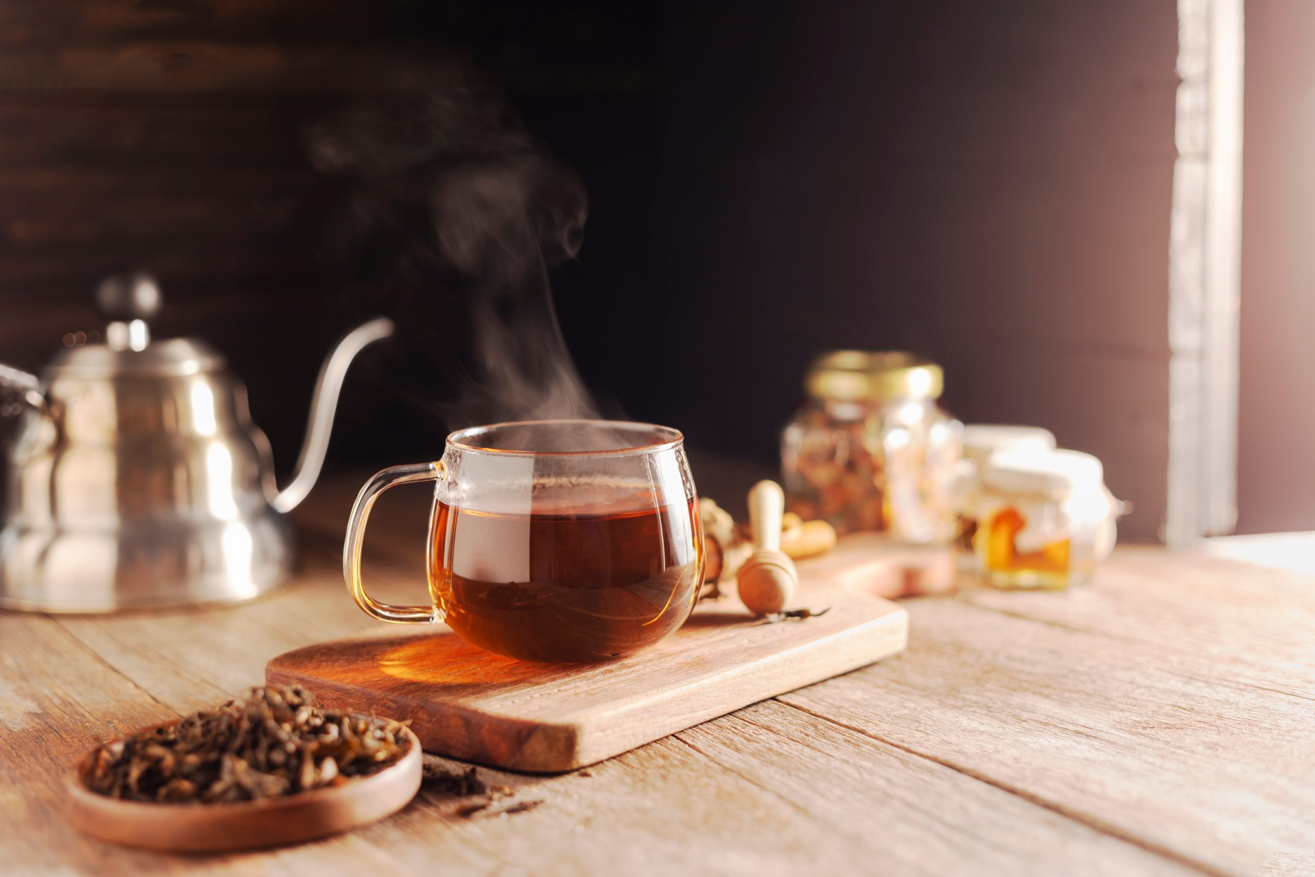 Glass cup of tea with steam rising, in the foreground 