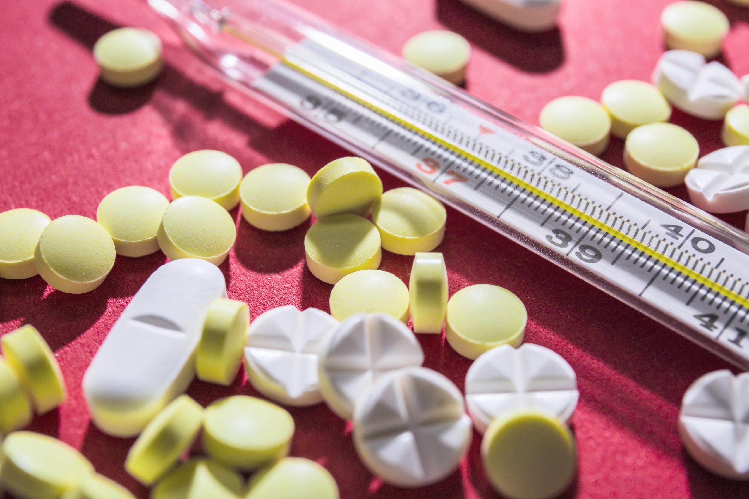 close up pills thermometer red background